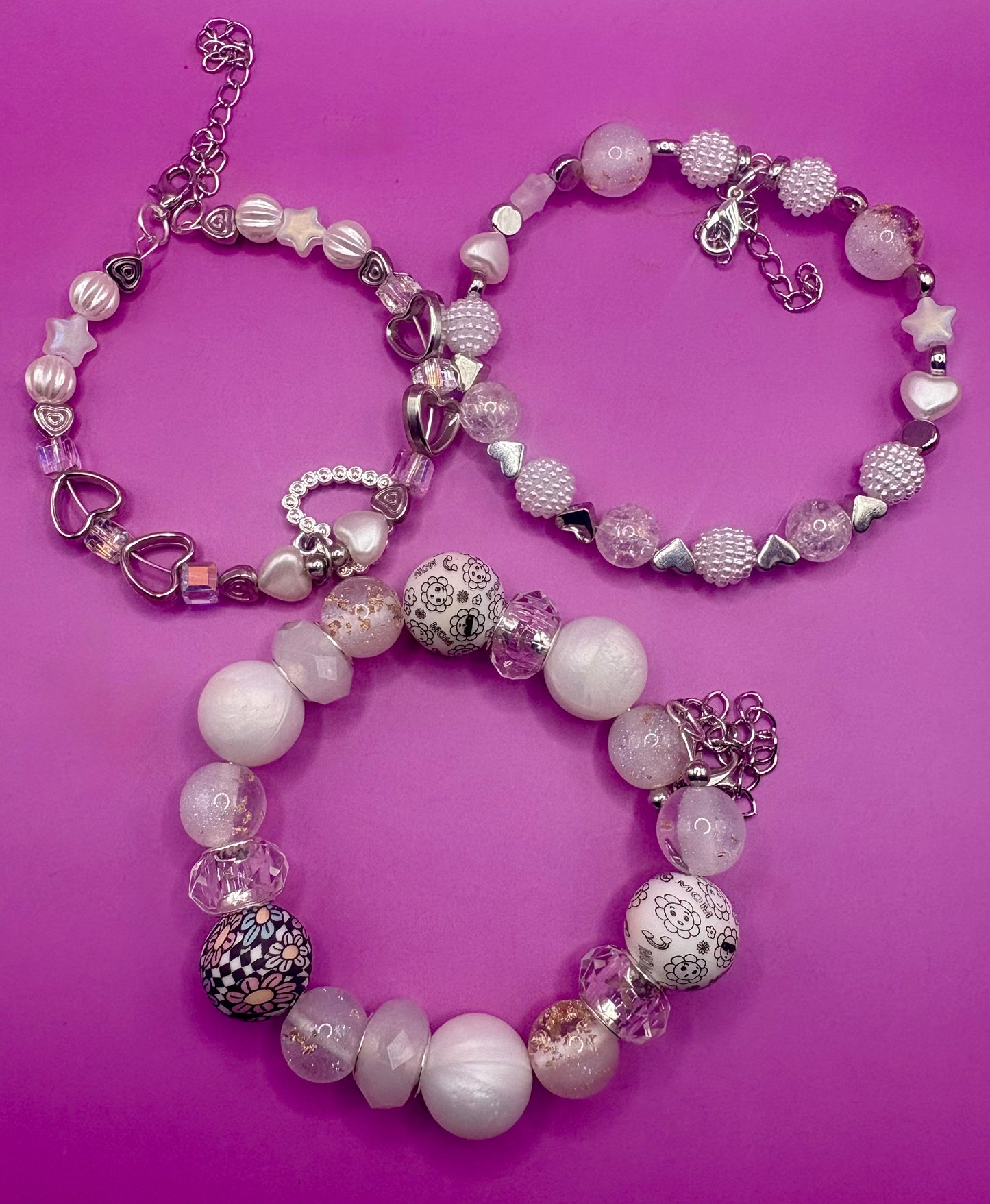 Handmade beaded charm bracelets stacked together, showcasing unique designs and vibrant colors, perfect for adding a personalized touch to any jewelry collection. white and silver hear pendant
