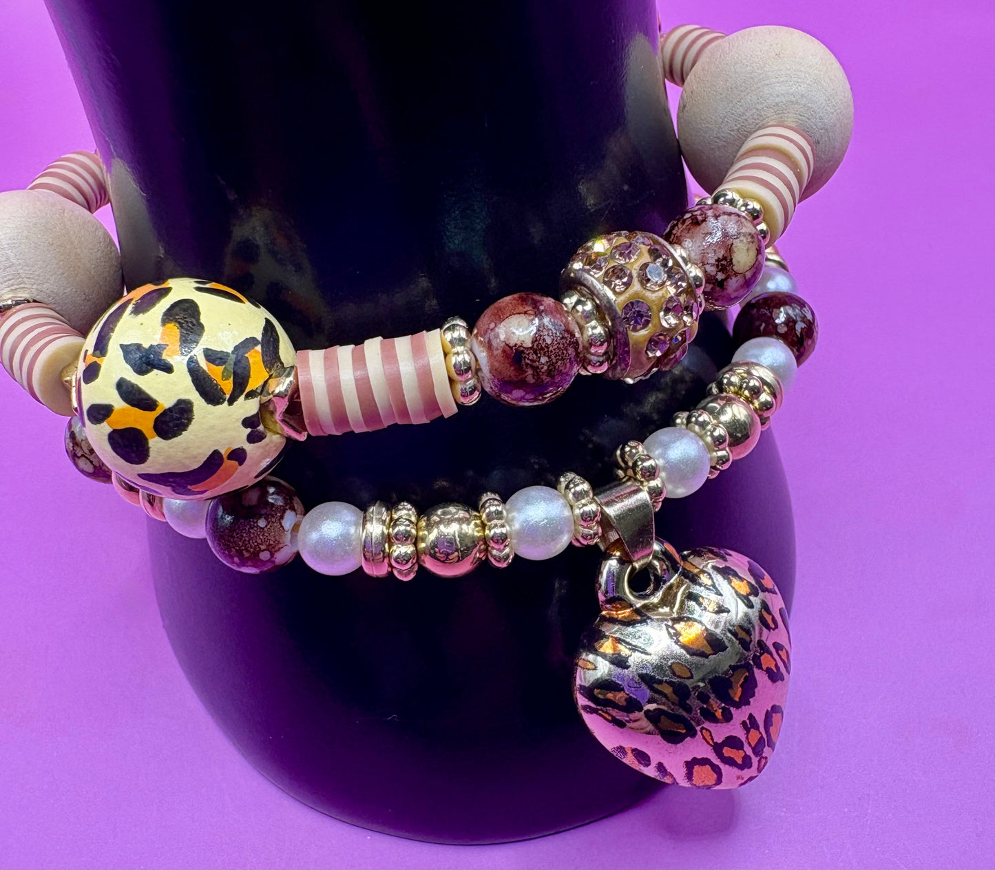 Handmade beaded charm bracelets stacked together, showcasing unique designs and vibrant colors, perfect for adding a personalized touch to any jewelry collection. tan brown leopard print animal print heart pendant