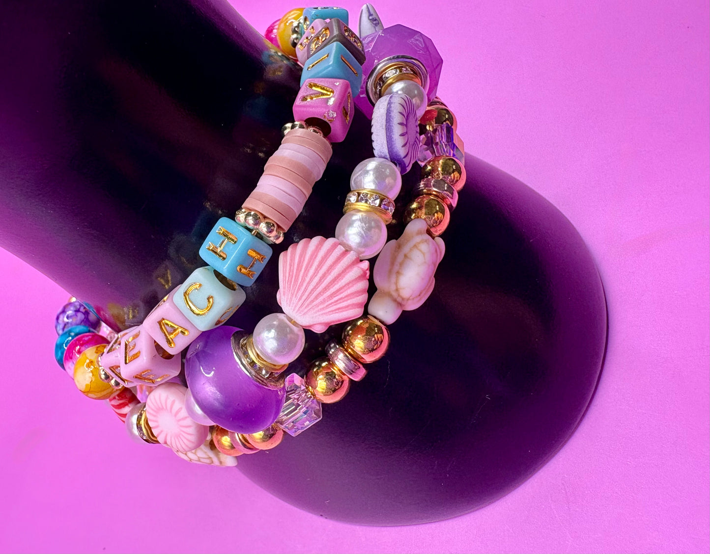 Handmade beaded charm bracelets stacked together, showcasing unique designs and vibrant colors, perfect for adding a personalized touch to any jewelry collection. beach vibes turtles seal life purple