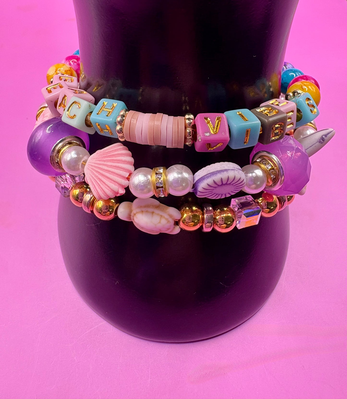 Handmade beaded charm bracelets stacked together, showcasing unique designs and vibrant colors, perfect for adding a personalized touch to any jewelry collection. beach vibes turtles seal life purple