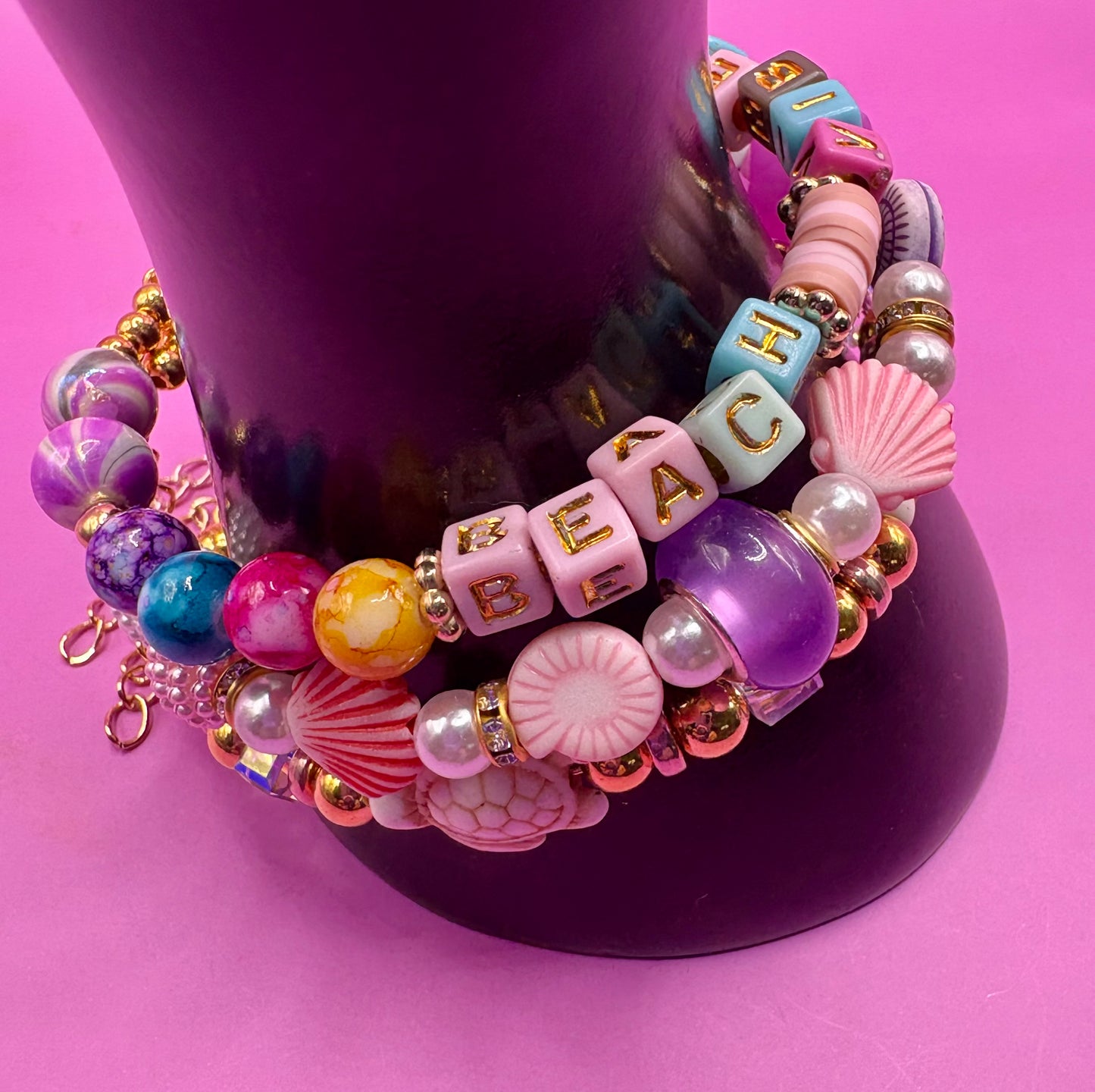 Handmade beaded charm bracelets stacked together, showcasing unique designs and vibrant colors, perfect for adding a personalized touch to any jewelry collection. beach vibes turtles seal life purple
