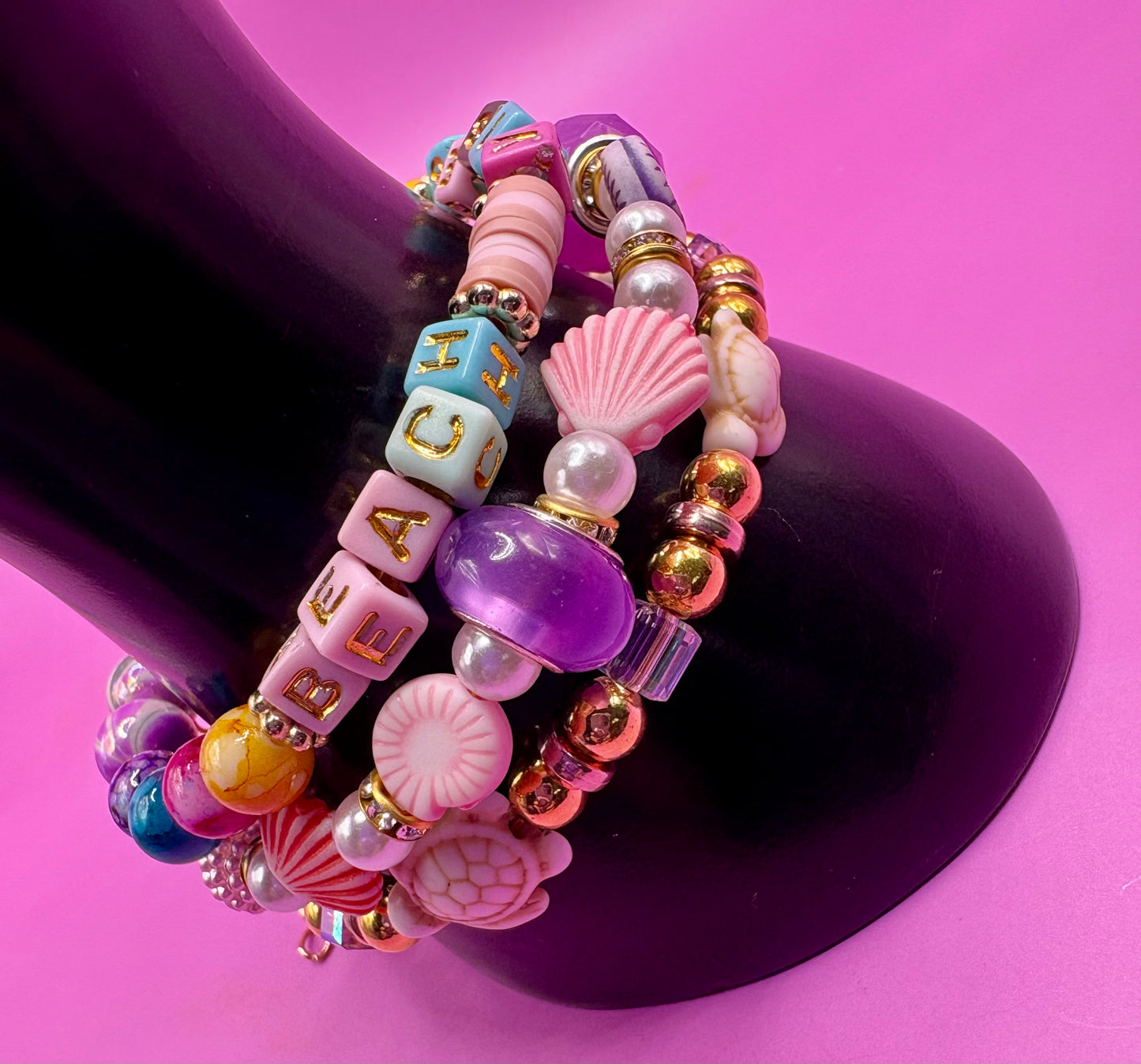 Handmade beaded charm bracelets stacked together, showcasing unique designs and vibrant colors, perfect for adding a personalized touch to any jewelry collection. beach vibes turtles seal life purple