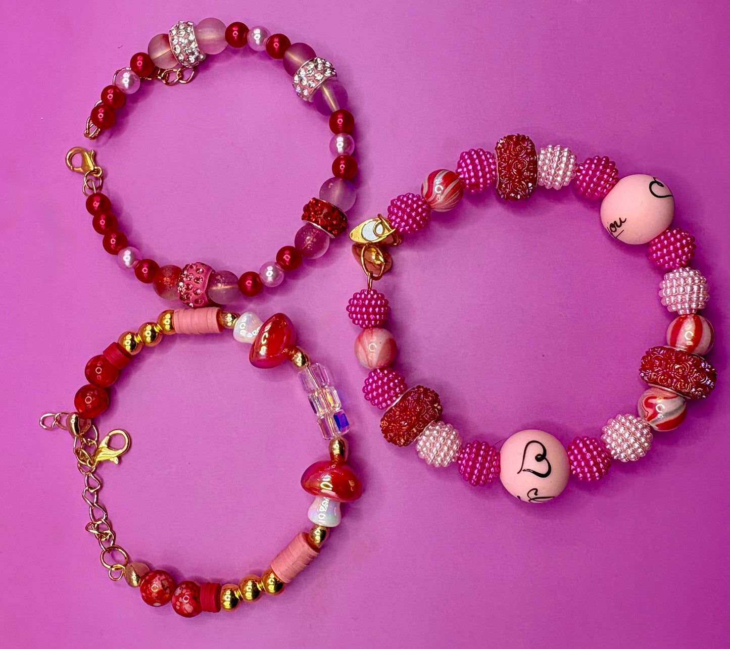 Handmade beaded charm bracelets stacked together, showcasing unique designs and vibrant colors, perfect for adding a personalized touch to any jewelry collection. red toadstool fairy I love you romantic bracelet