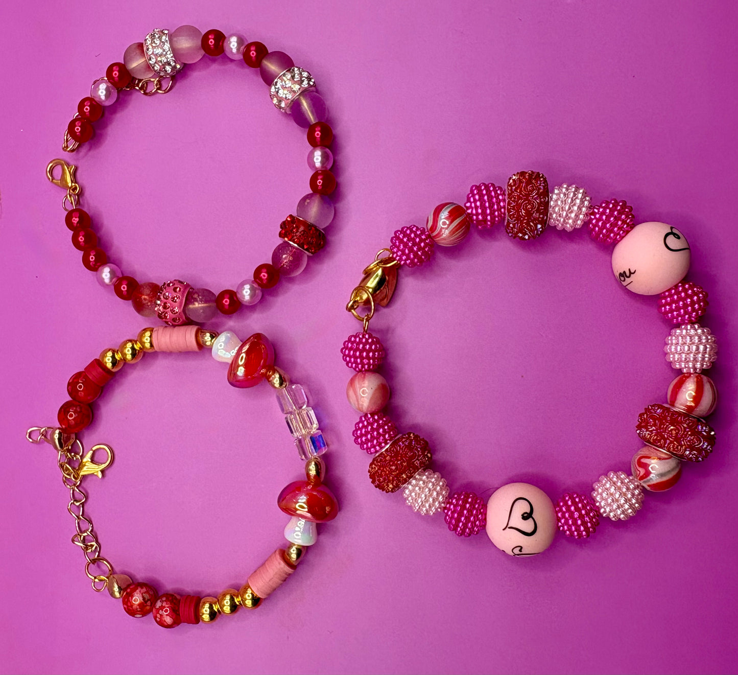 Handmade beaded charm bracelets stacked together, showcasing unique designs and vibrant colors, perfect for adding a personalized touch to any jewelry collection. red toadstool fairy I love you romantic bracelet