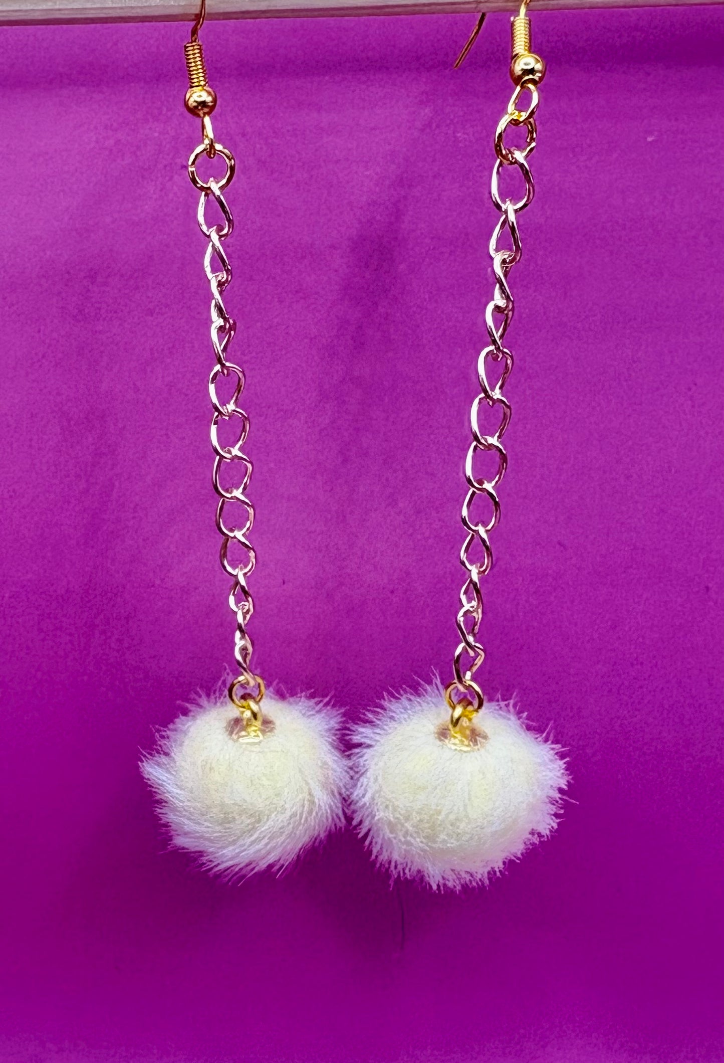 Trendy long dangly drop earrings with fluffy pom pom embellishments, perfect for adding a playful and stylish touch to your accessory collection for any occasion.