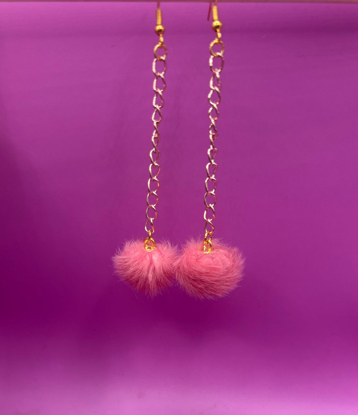 Trendy long dangly drop earrings with fluffy pom pom embellishments, perfect for adding a playful and stylish touch to your accessory collection for any occasion.