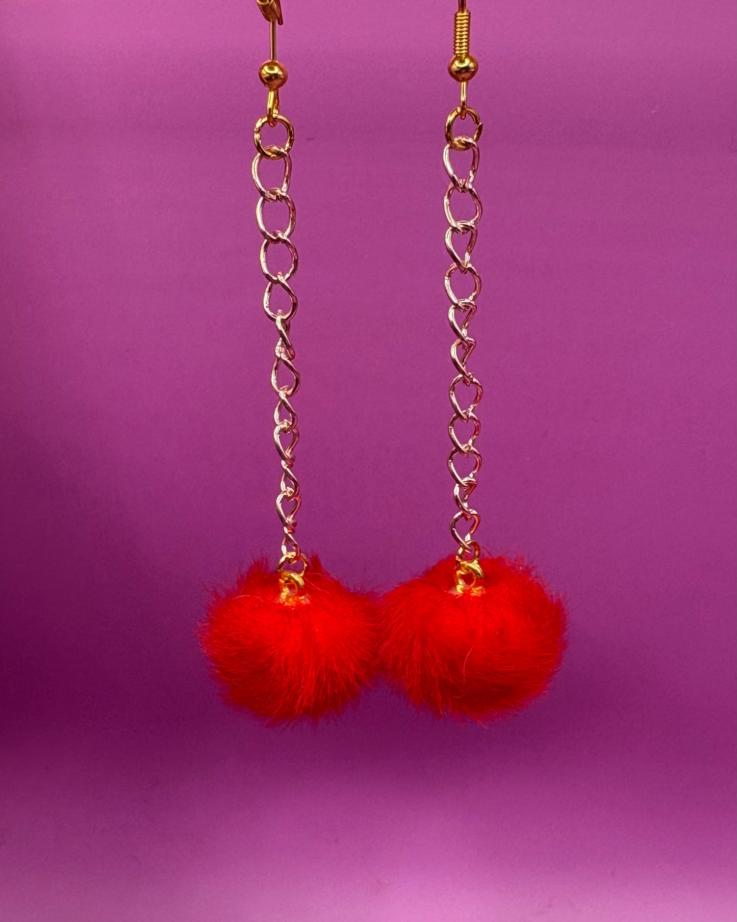 Trendy long dangly drop earrings with fluffy pom pom embellishments, perfect for adding a playful and stylish touch to your accessory collection for any occasion.