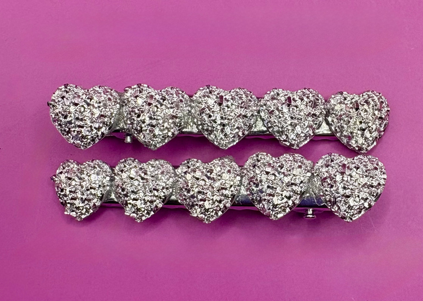 Charming heart-shaped circular glitter hair slides in silver, perfect for festive hairstyles and holiday parties, sold in pairs, each measuring 6cm.