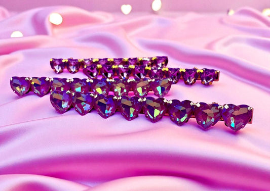 Purple heart-shaped rhinestone hair clips on a pink fabric background