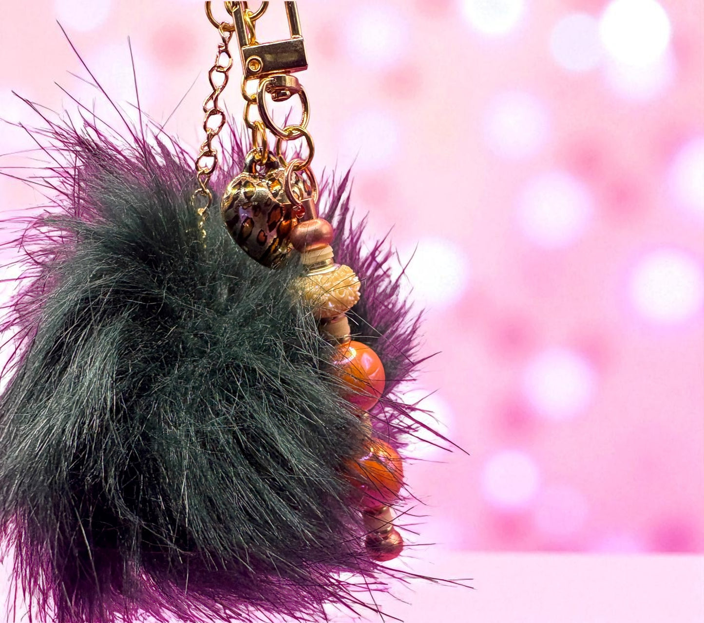 Fuzzy keychain with beads on a pink and white blurred background