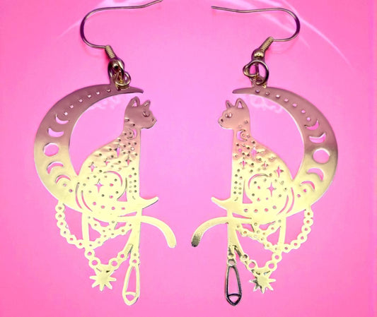 Luminous cat-shaped earrings on a pink background