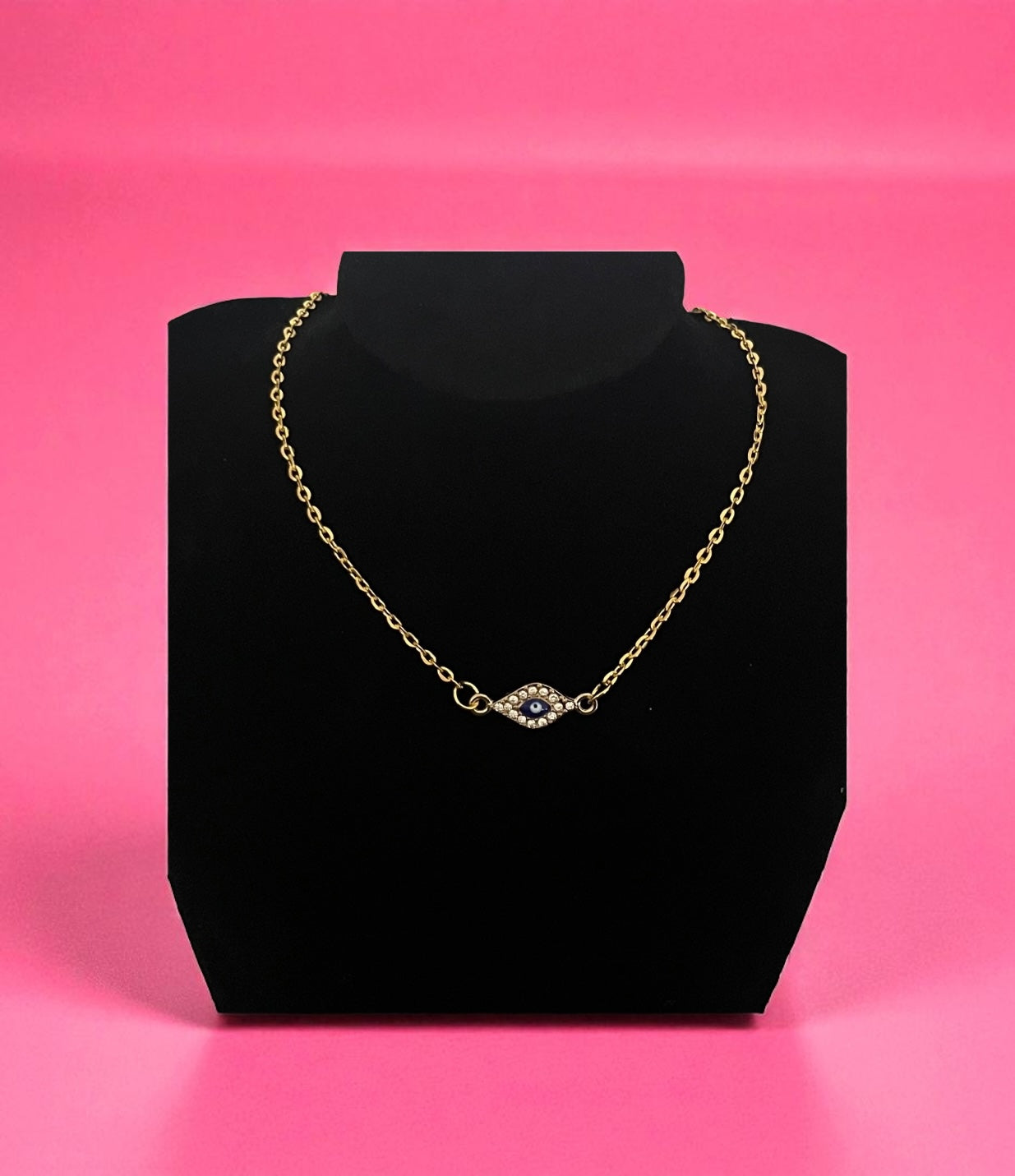 Gold necklace with a clasp on a black bust against a pink background