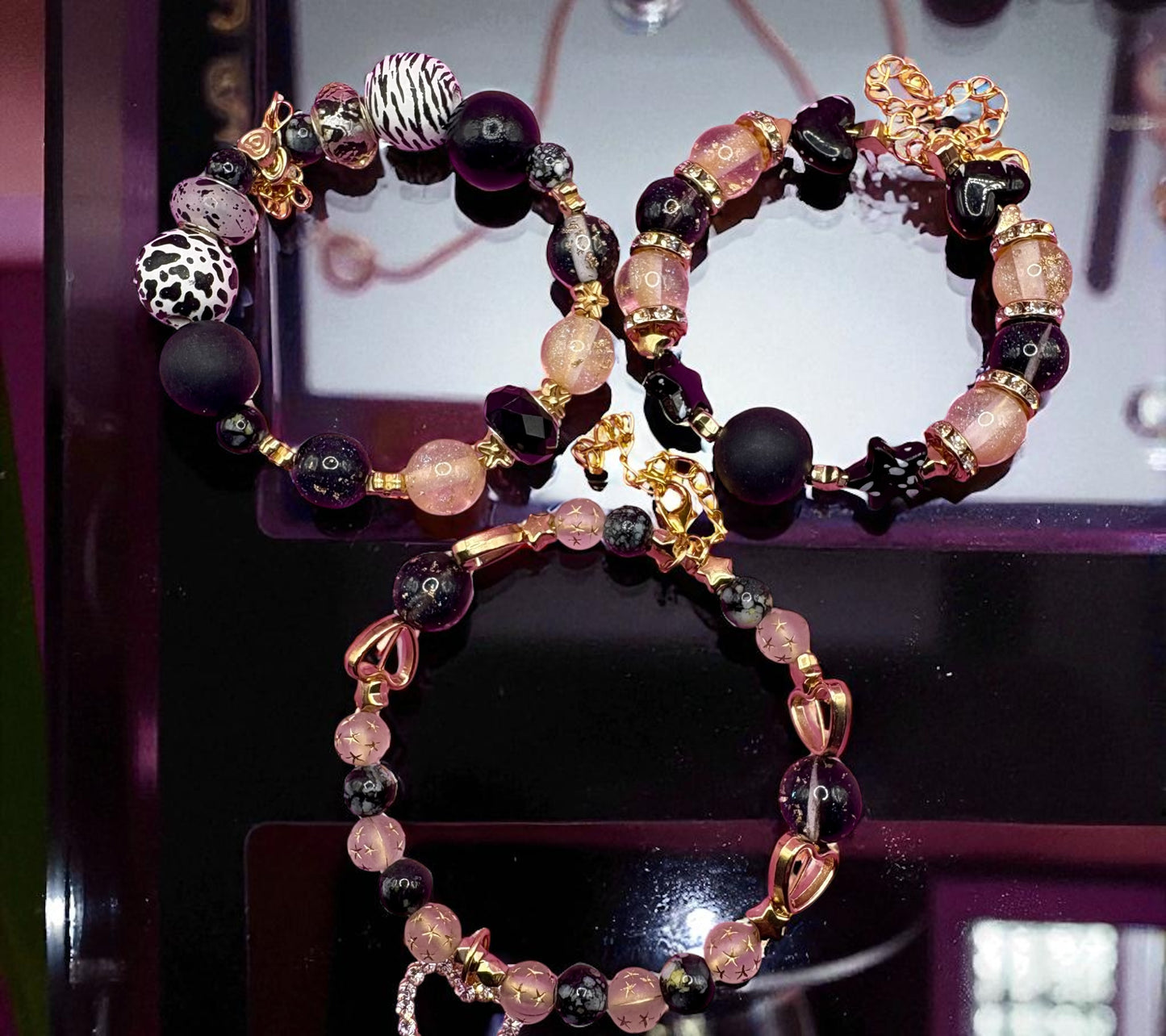 Beaded bracelet with black, pink, and gold beads on a dark surface