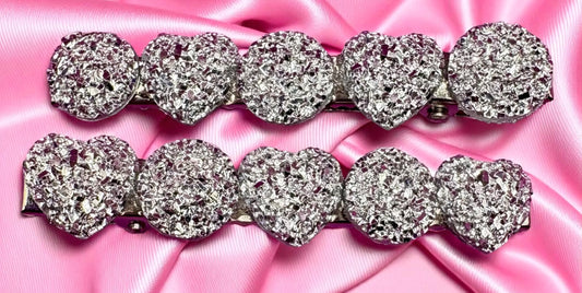 Silver heart-shaped hair clips  on a pink satin background