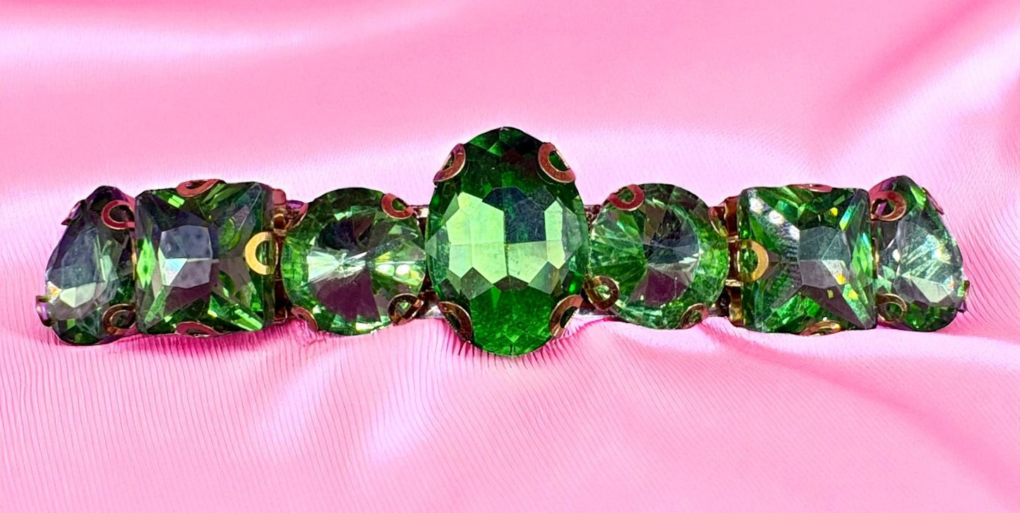 Green crystal hair clips on a pink fabric background