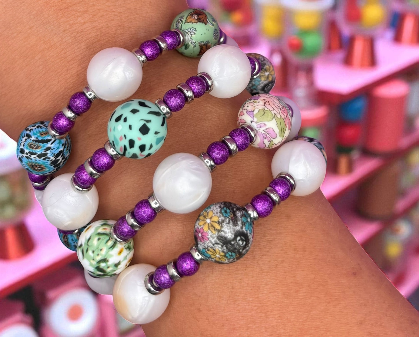 Colorful beaded bracelets on a wrist with a blurred background of colorful objects.