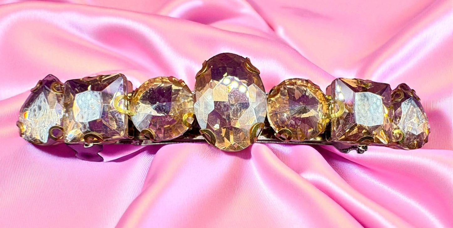 Decorative hair barrette with crystals on a pink satin background