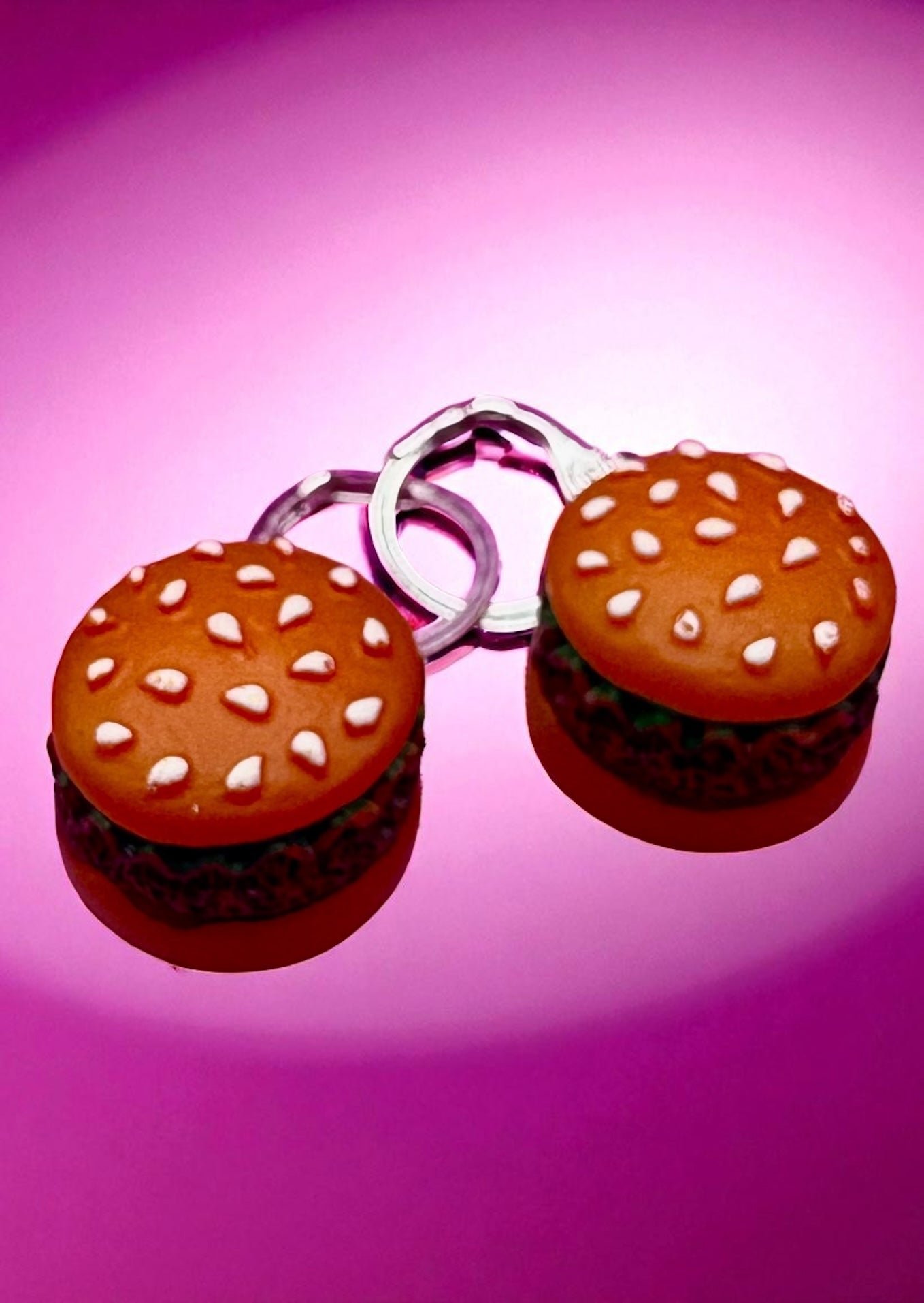 Hamburger-shaped earrings on a pink background