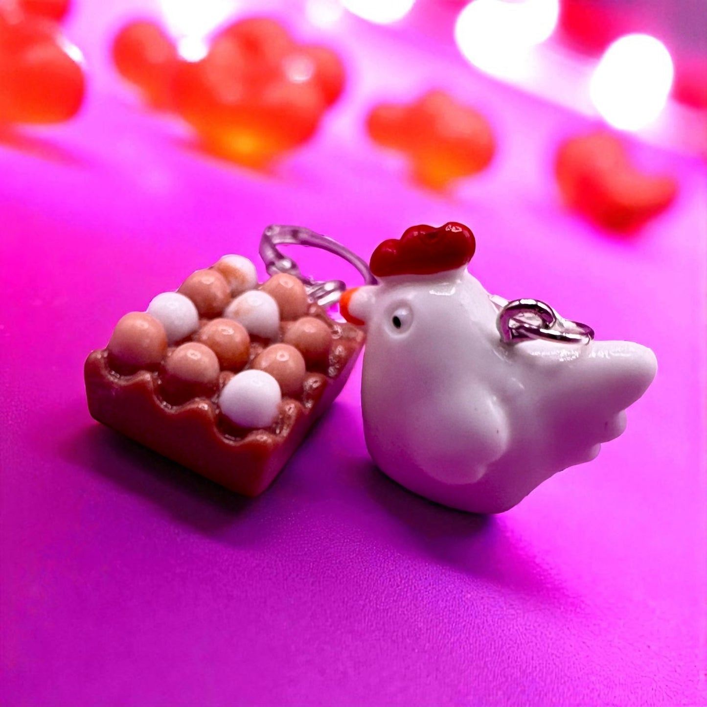 Chicken and nest earrings on a pink background with heart shapes