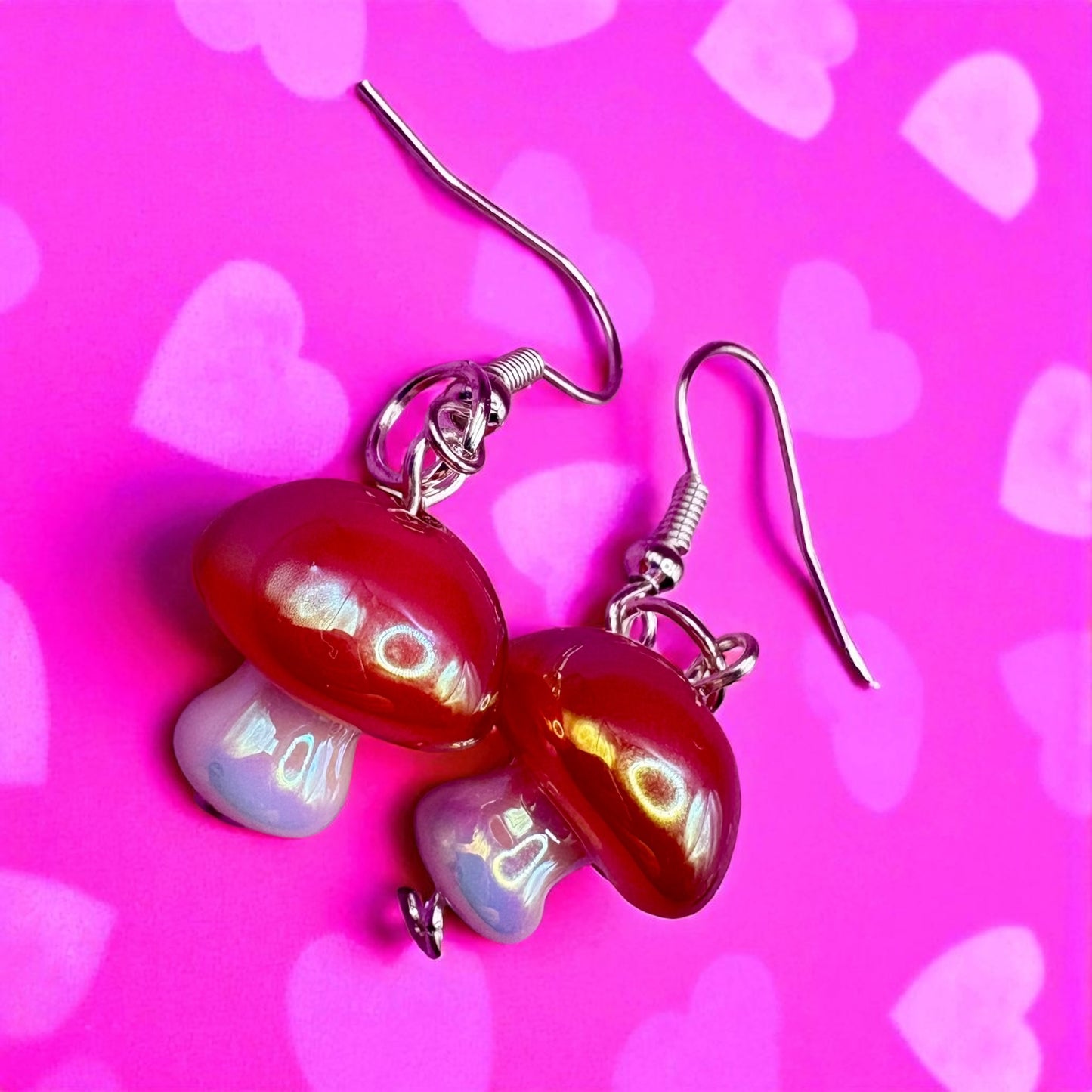 Butterfly-shaped earrings on a pink background with heart patterns