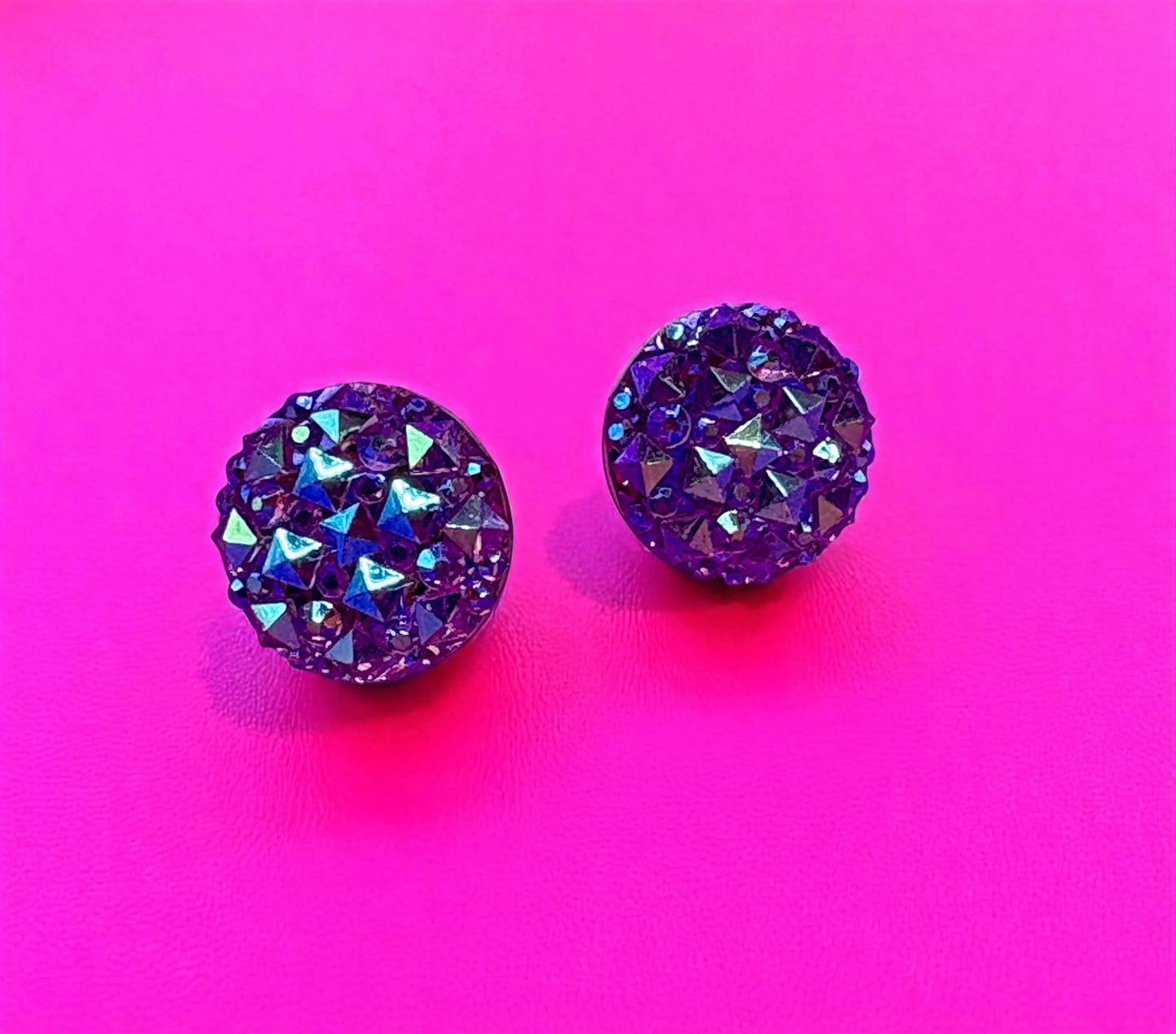 Purple crystal stud earrings on a pink background
