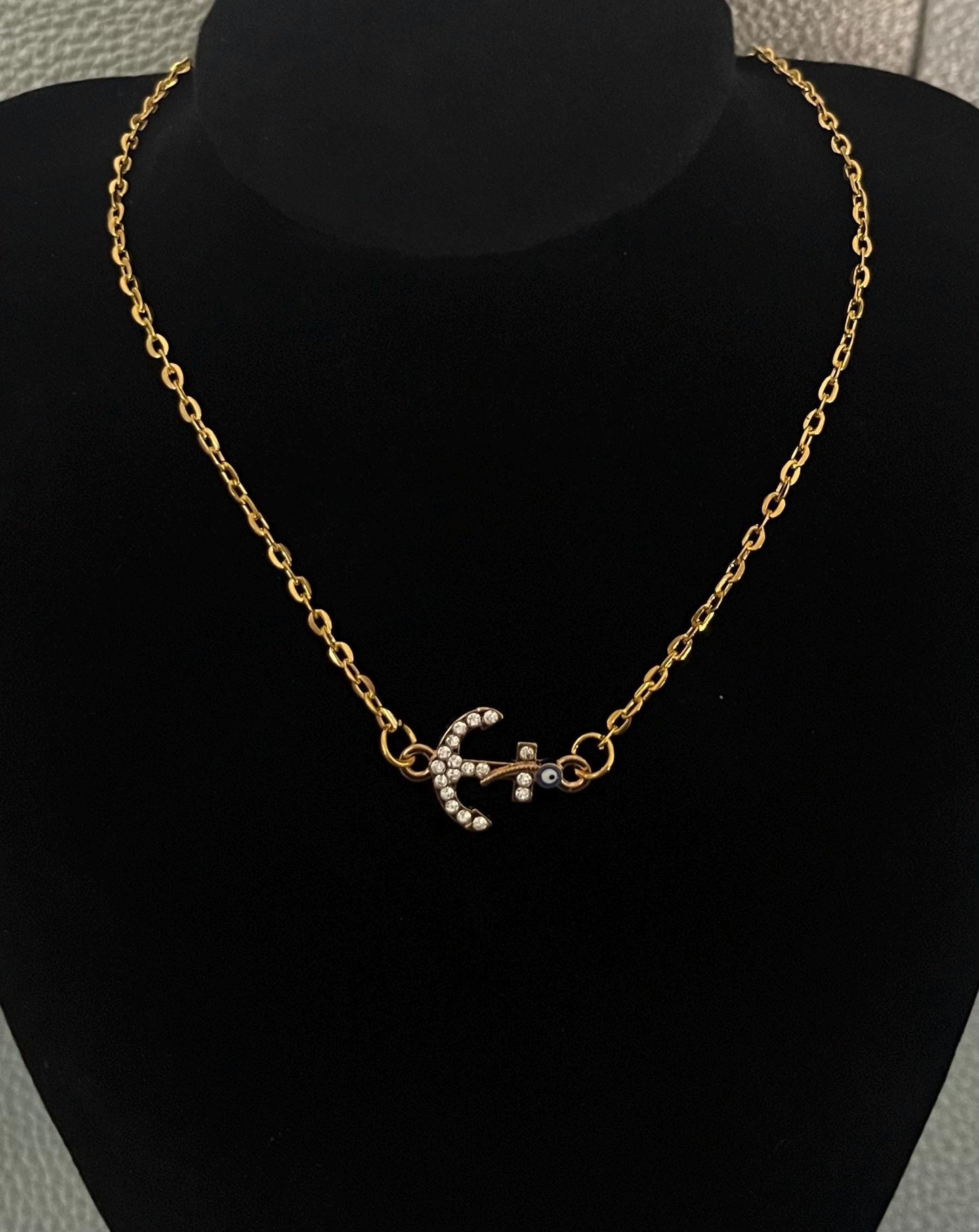 Stylish diamante anchor pendant necklace featuring a protective evil eye charm, perfect for adding a touch of nautical elegance and protection to any outfit.
