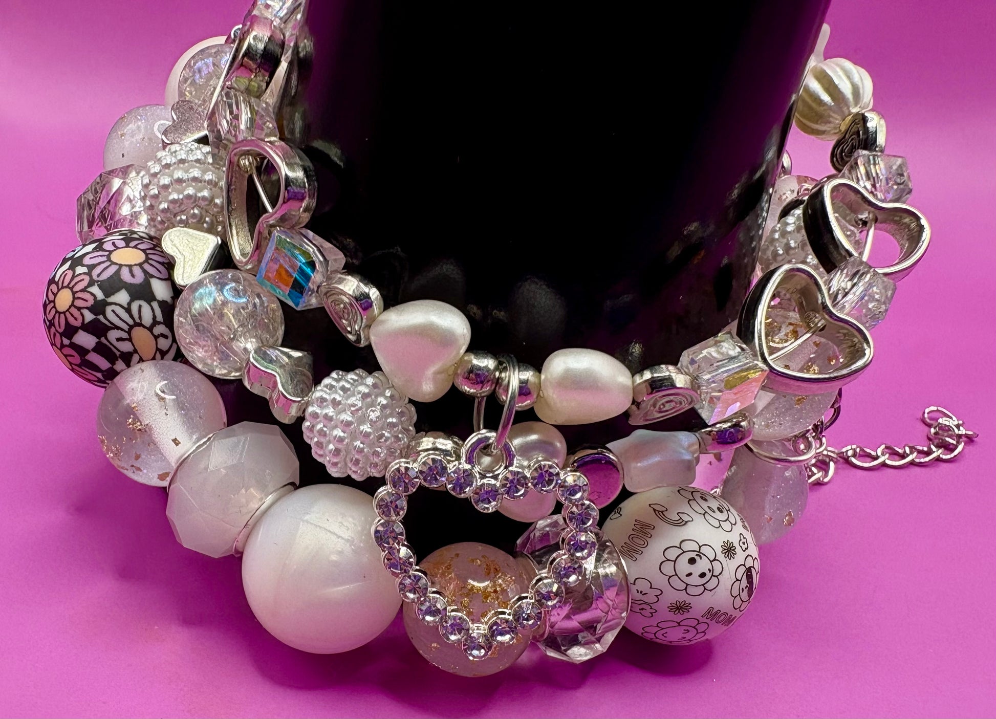 Handmade beaded charm bracelets stacked together, showcasing unique designs and vibrant colors, perfect for adding a personalized touch to any jewelry collection. white and silver hear pendant