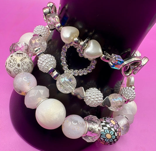 Handmade beaded charm bracelets stacked together, showcasing unique designs and vibrant colors, perfect for adding a personalized touch to any jewelry collection. white and silver hear pendant