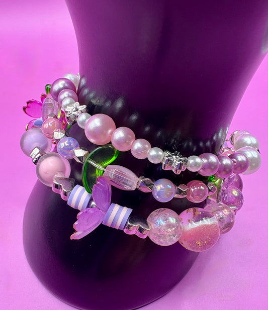 Handmade beaded charm bracelets stacked together, showcasing unique designs and vibrant colors, perfect for adding a personalized touch to any jewelry collection. purple flower tulip petals pink