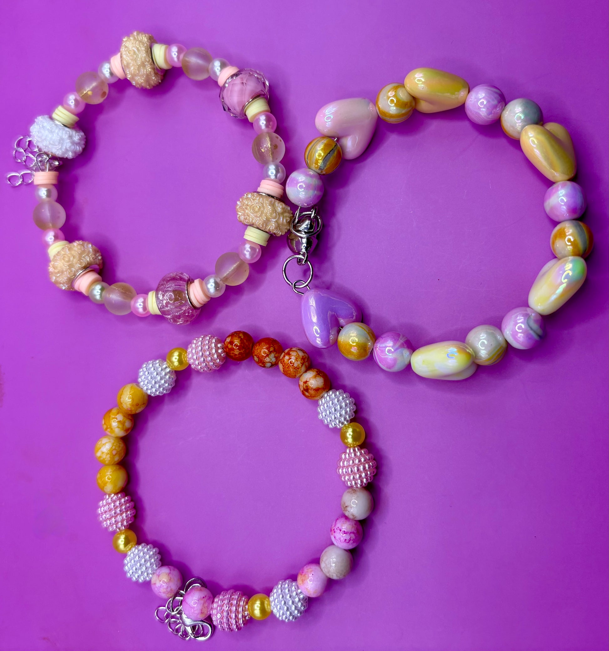Handmade beaded charm bracelets stacked together, showcasing unique designs and vibrant colors, perfect for adding a personalized touch to any jewelry collection. yellow floral love hearts pink orange