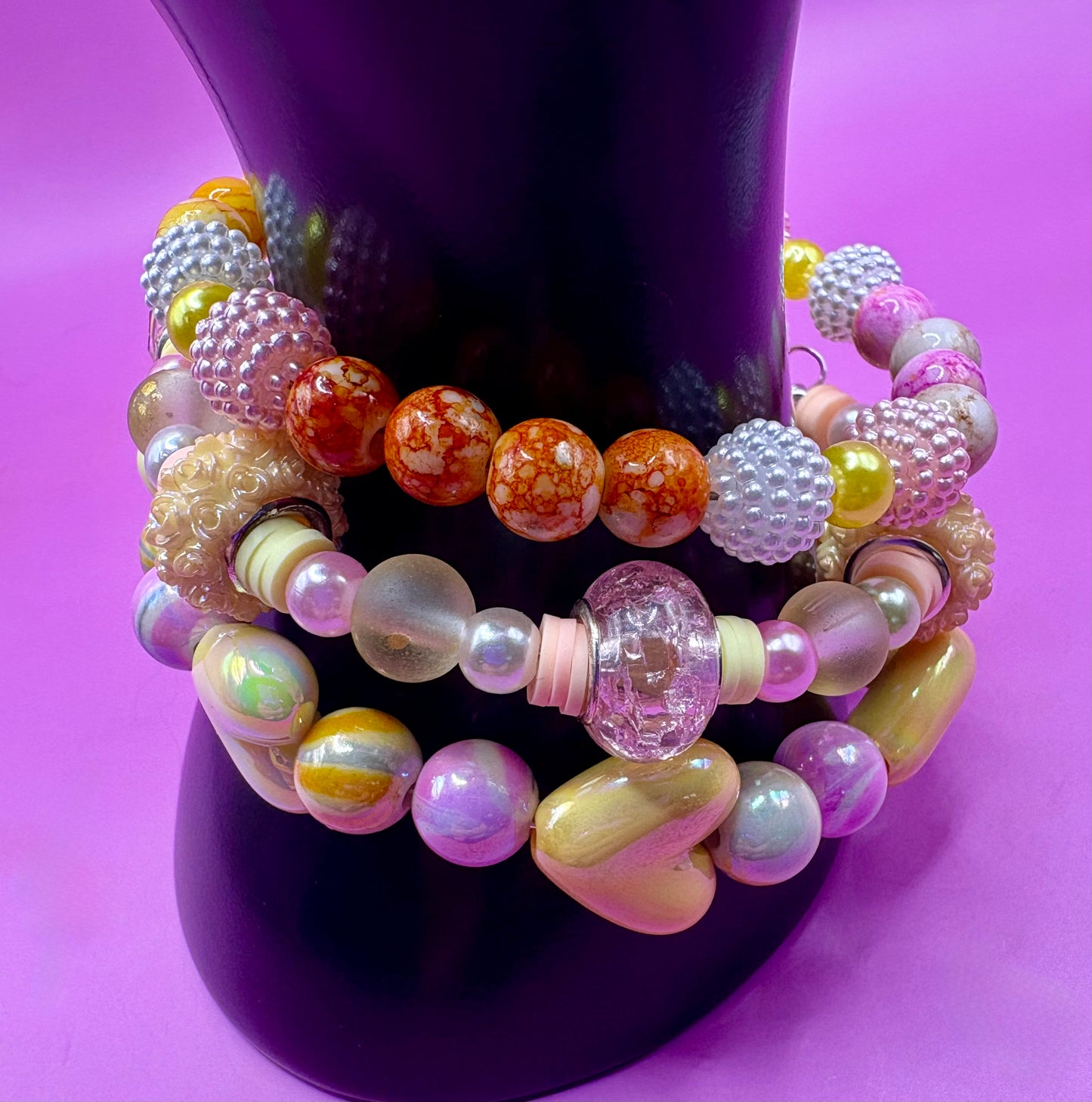 Handmade beaded charm bracelets stacked together, showcasing unique designs and vibrant colors, perfect for adding a personalized touch to any jewelry collection. yellow floral love hearts pink orange