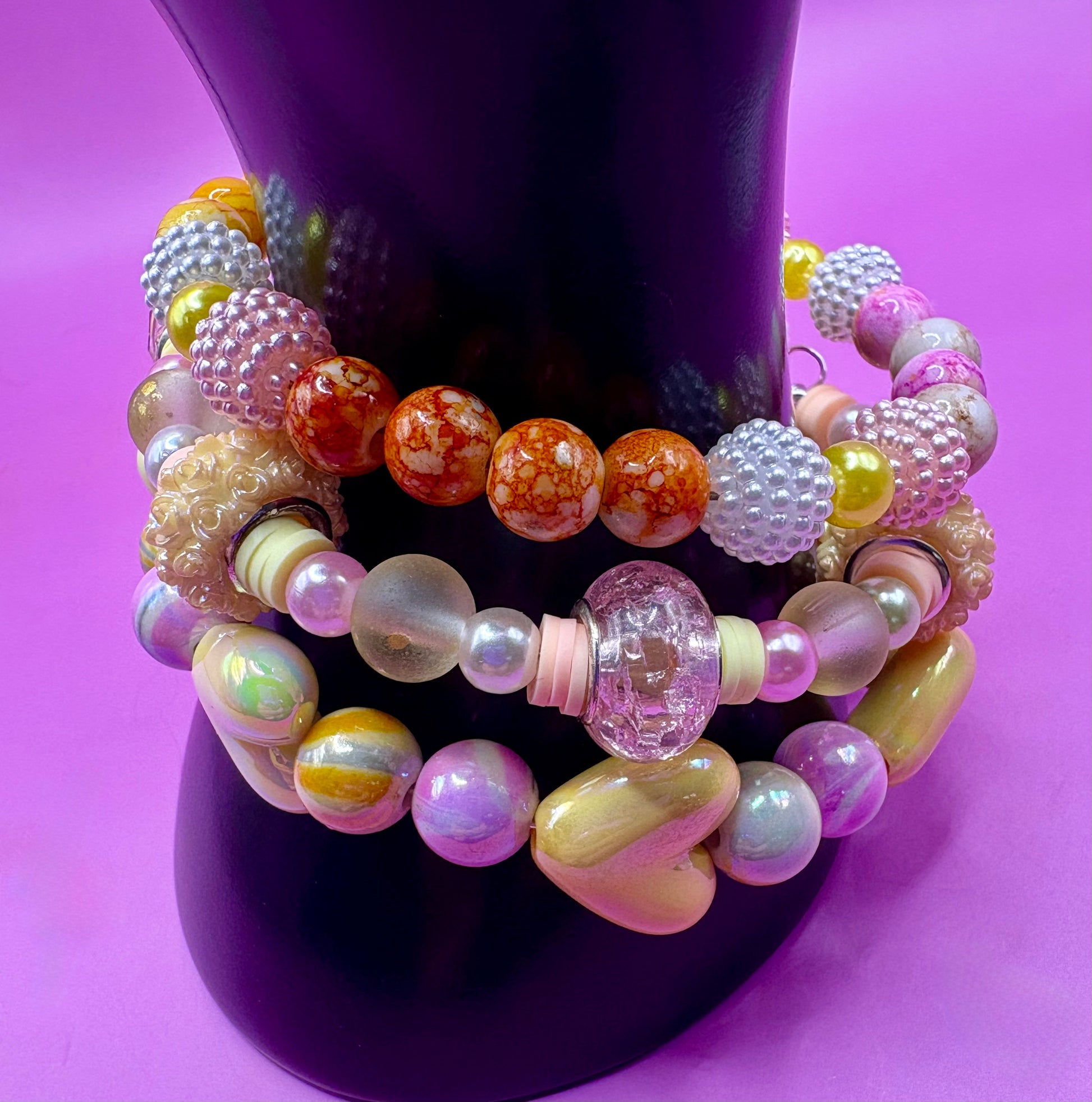 Handmade beaded charm bracelets stacked together, showcasing unique designs and vibrant colors, perfect for adding a personalized touch to any jewelry collection. yellow floral love hearts pink orange