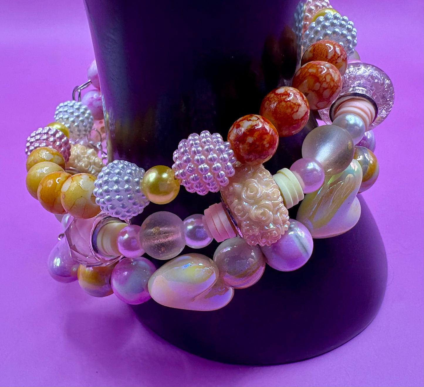 Handmade beaded charm bracelets stacked together, showcasing unique designs and vibrant colors, perfect for adding a personalized touch to any jewelry collection. yellow floral love hearts pink orange