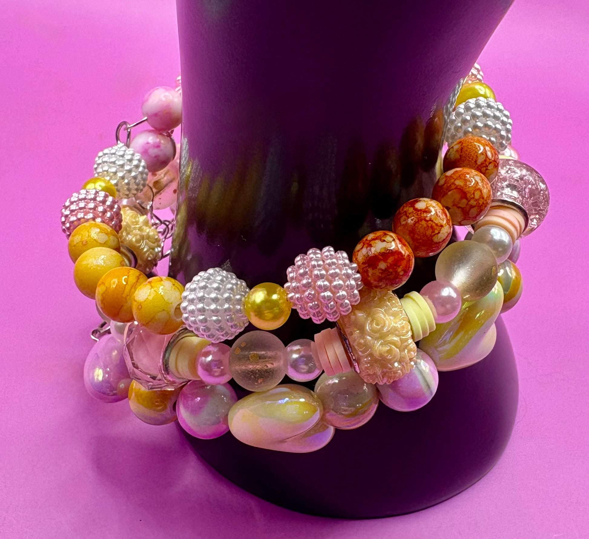 Handmade beaded charm bracelets stacked together, showcasing unique designs and vibrant colors, perfect for adding a personalized touch to any jewelry collection. yellow floral love hearts pink orange