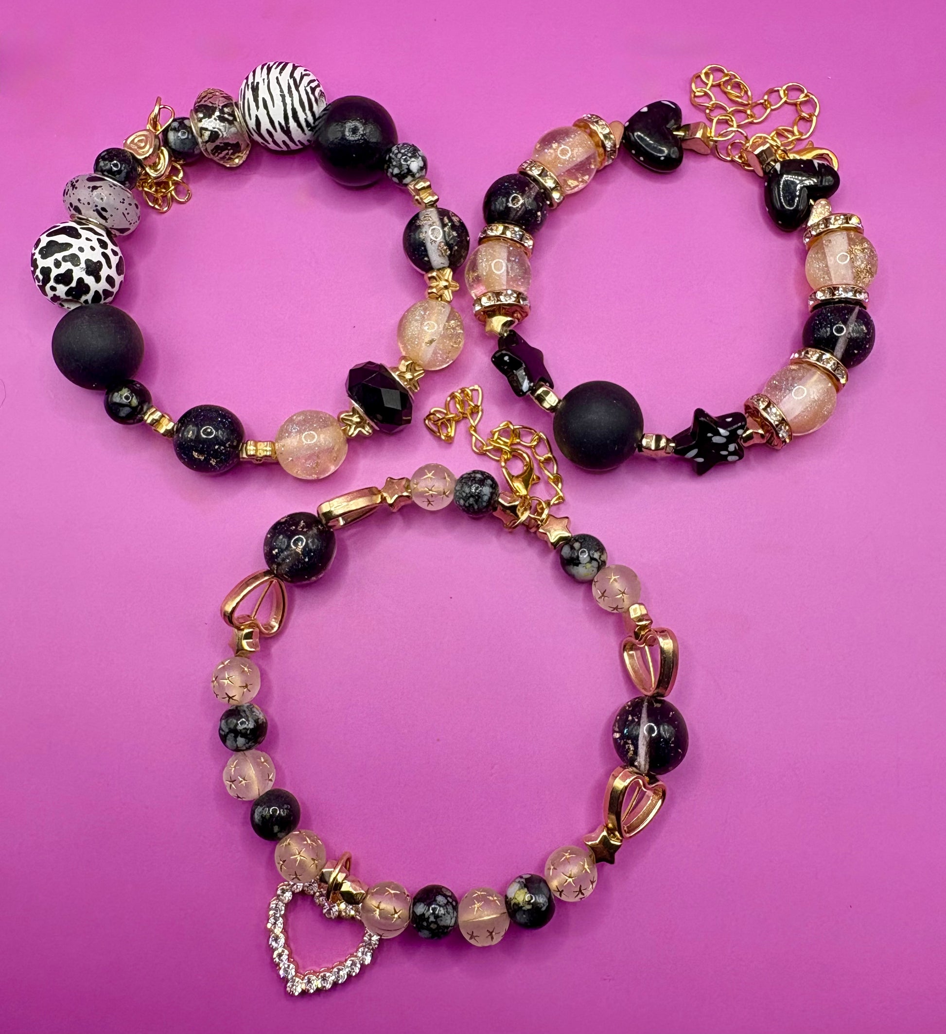 Handmade beaded charm bracelets stacked together, showcasing unique designs and vibrant colors, perfect for adding a personalized touch to any jewelry collection.  black gold heart pendant
