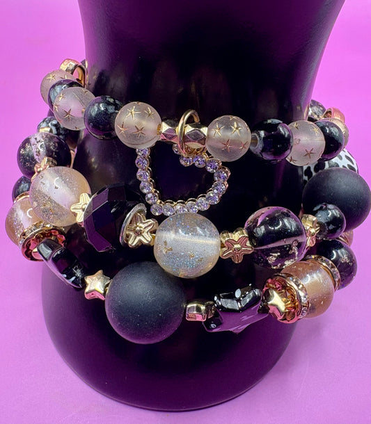 Handmade beaded charm bracelets stacked together, showcasing unique designs and vibrant colors, perfect for adding a personalized touch to any jewelry collection.  black gold heart pendant