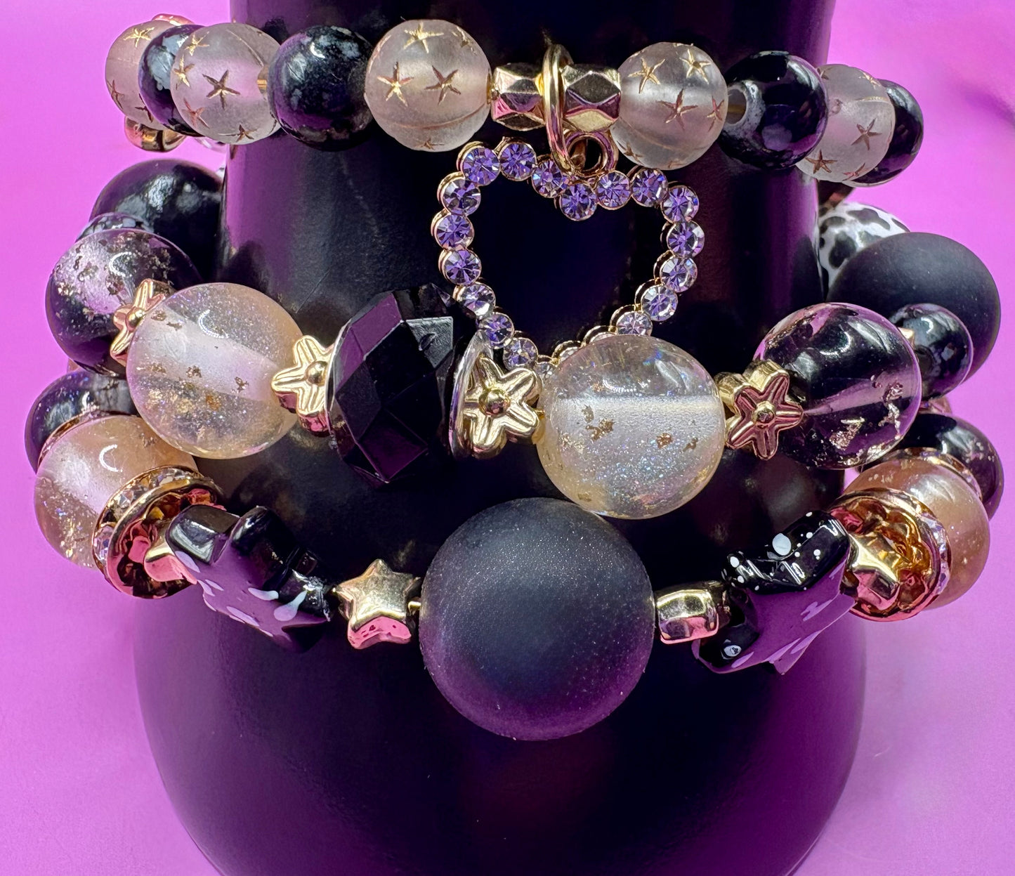 Handmade beaded charm bracelets stacked together, showcasing unique designs and vibrant colors, perfect for adding a personalized touch to any jewelry collection.  black gold heart pendant