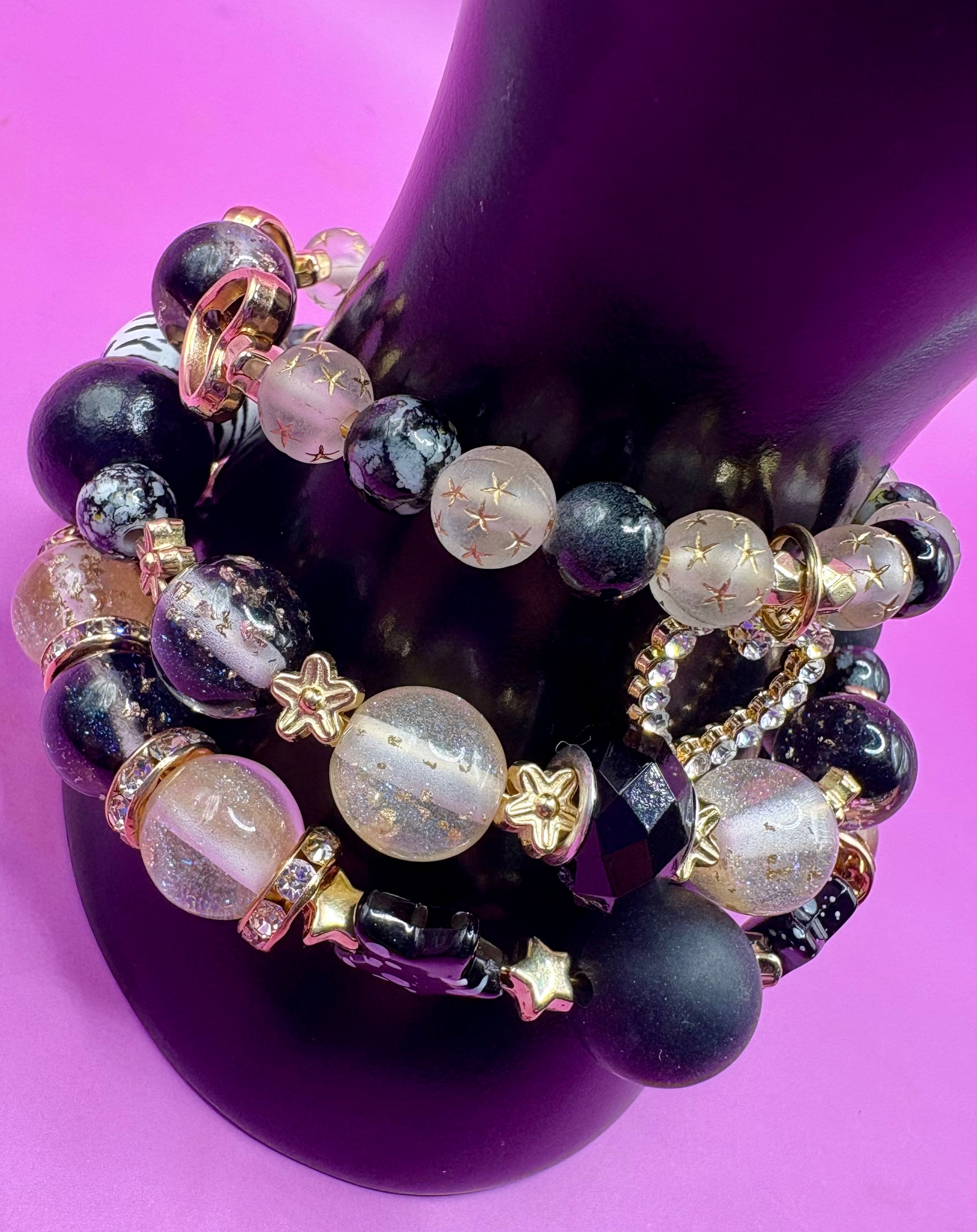 Handmade beaded charm bracelets stacked together, showcasing unique designs and vibrant colors, perfect for adding a personalized touch to any jewelry collection.  black gold heart pendant