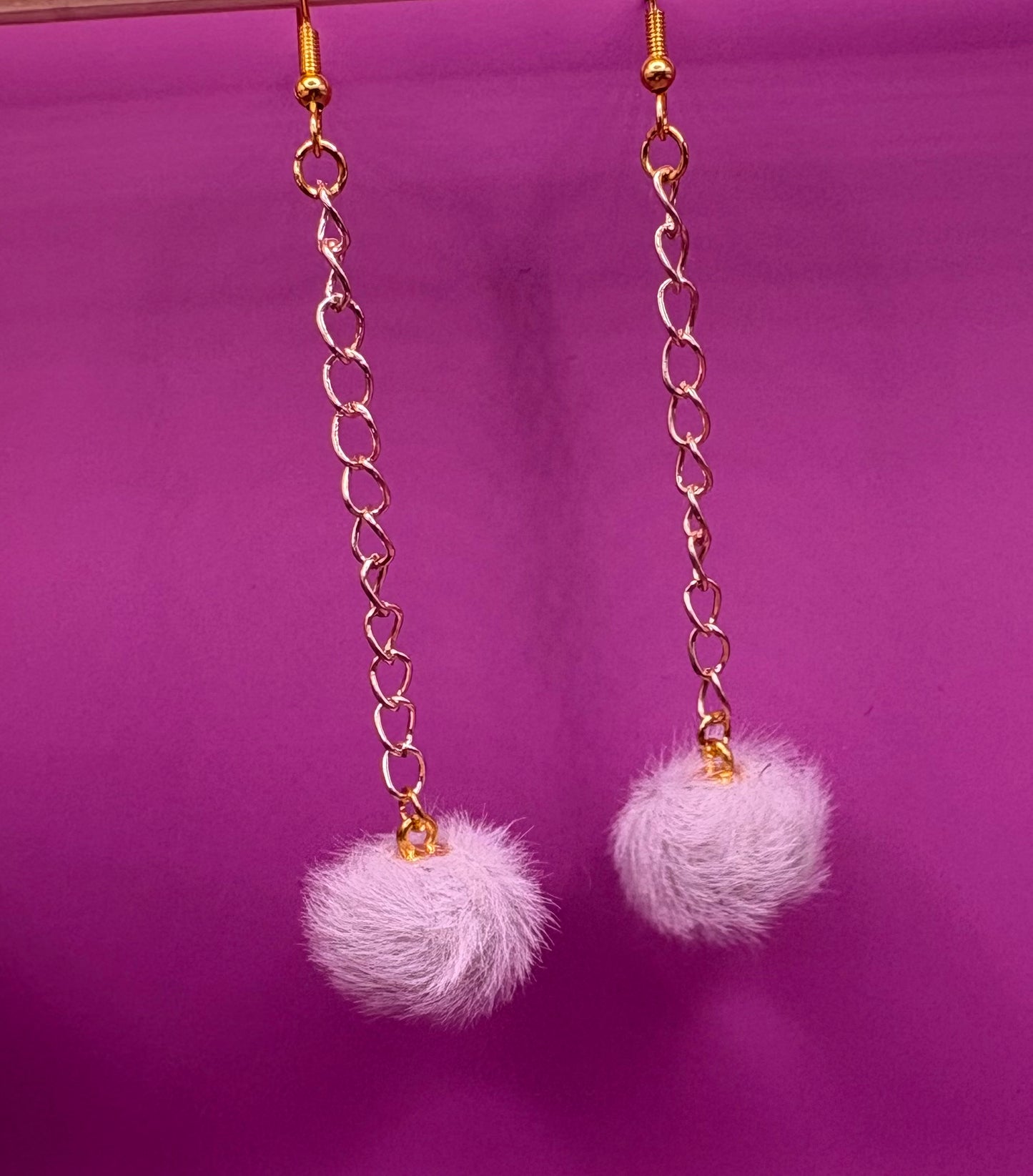 Trendy long dangly drop earrings with fluffy pom pom embellishments, perfect for adding a playful and stylish touch to your accessory collection for any occasion.