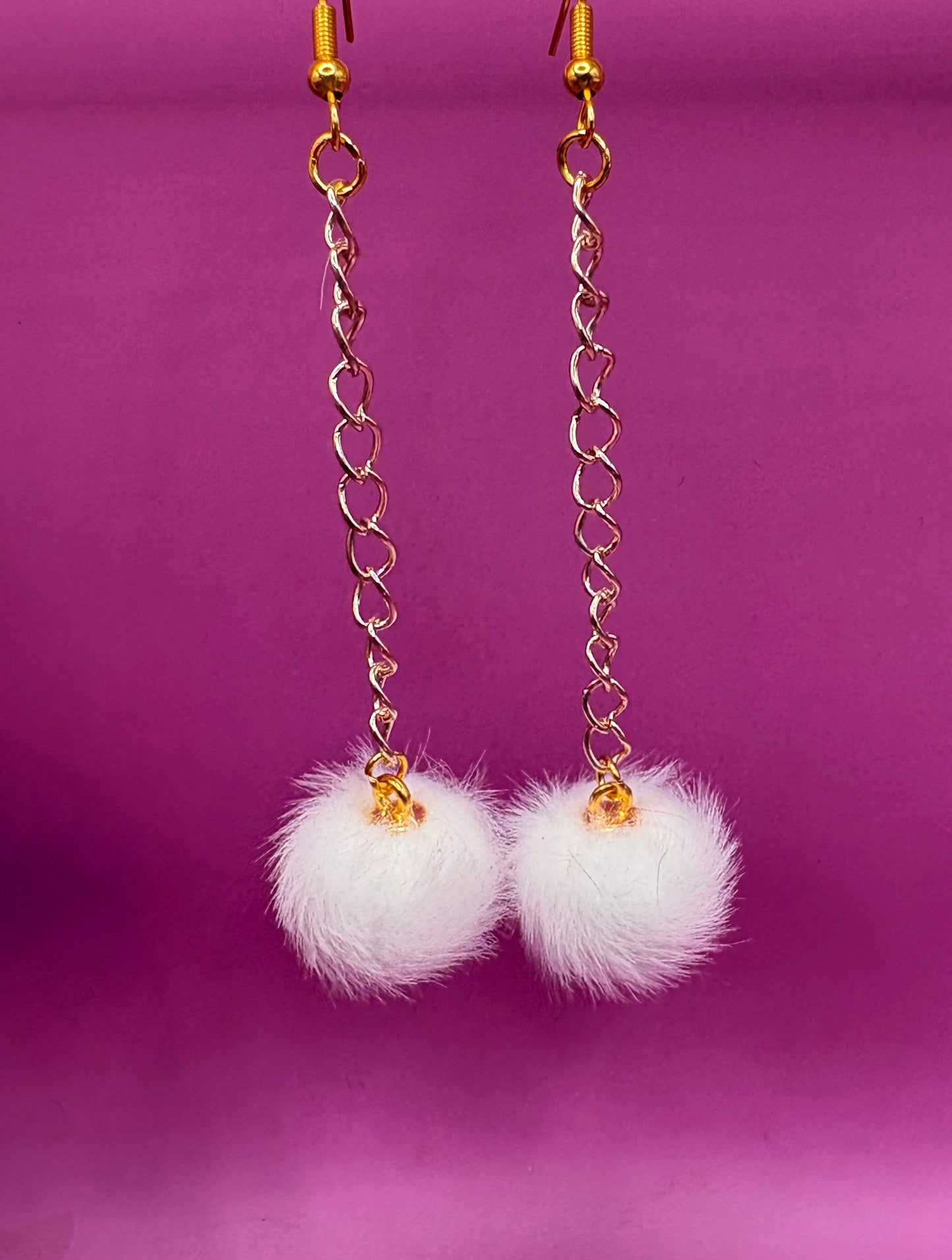 Trendy long dangly drop earrings with fluffy pom pom embellishments, perfect for adding a playful and stylish touch to your accessory collection for any occasion.