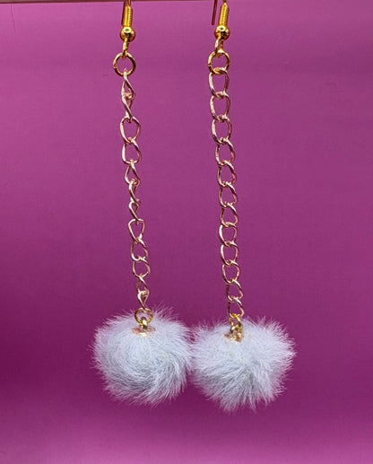 Trendy long dangly drop earrings with fluffy pom pom embellishments, perfect for adding a playful and stylish touch to your accessory collection for any occasion.