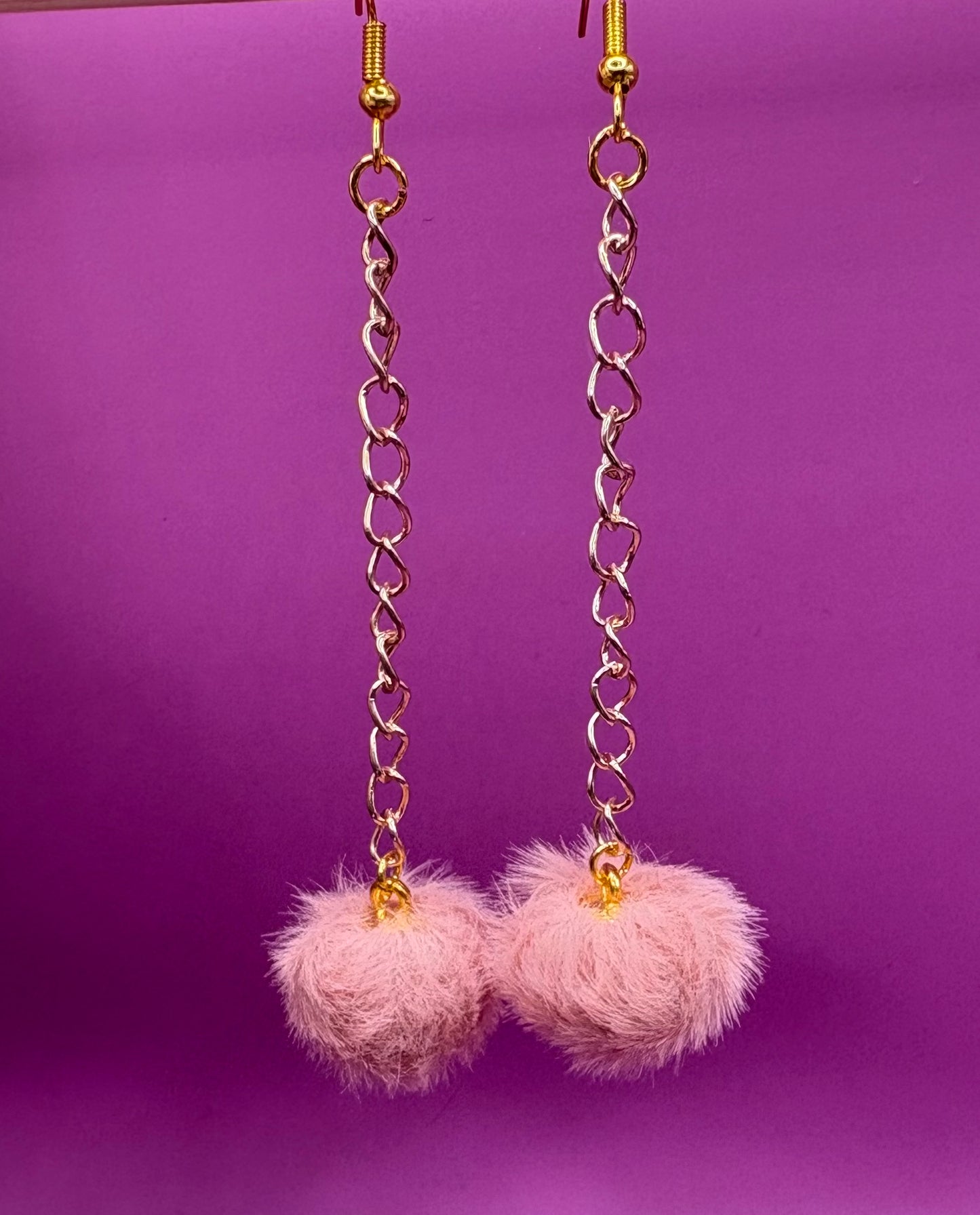 Trendy long dangly drop earrings with fluffy pom pom embellishments, perfect for adding a playful and stylish touch to your accessory collection for any occasion.
