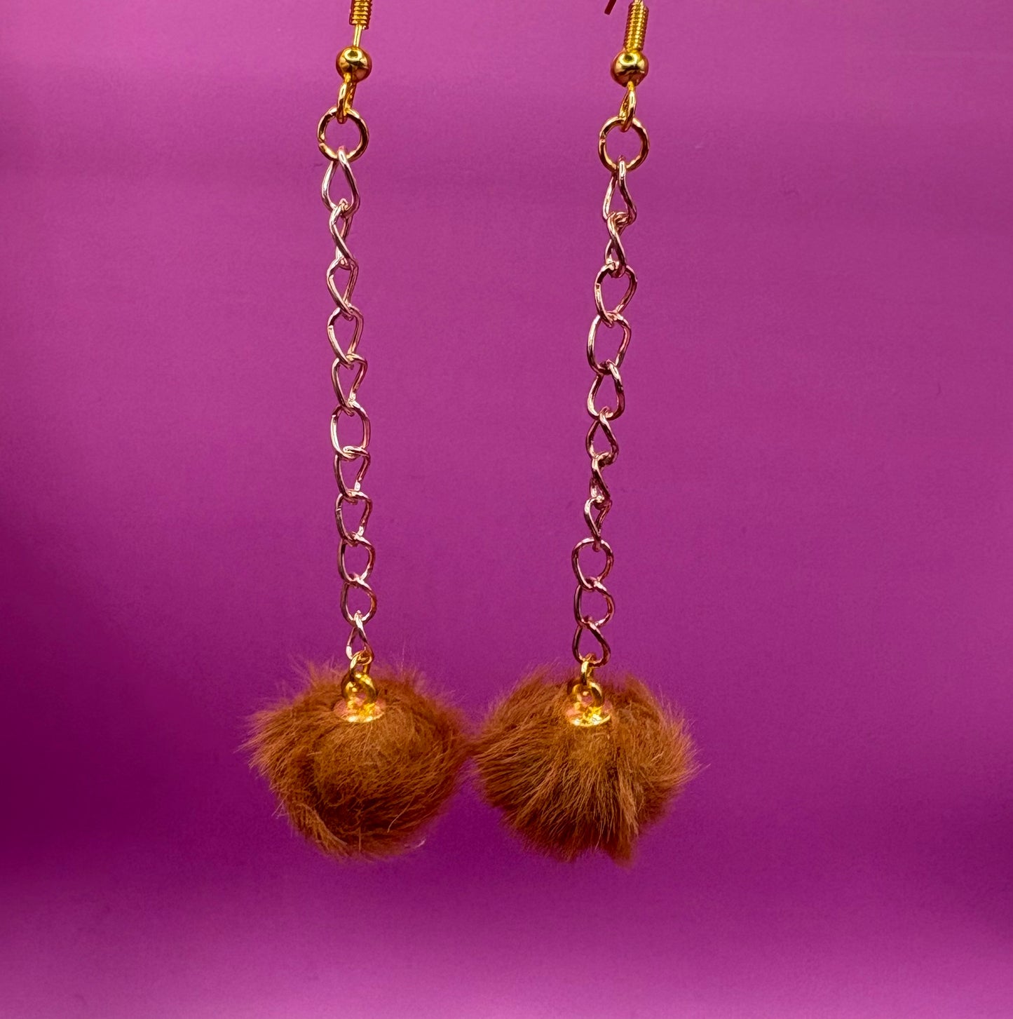 Trendy long dangly drop earrings with fluffy pom pom embellishments, perfect for adding a playful and stylish touch to your accessory collection for any occasion.