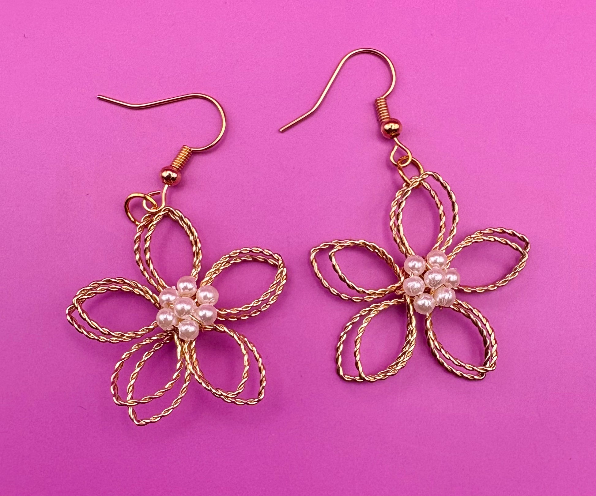 Elegant gold look flower dangly earrings with a pearly center, perfect for adding a touch of sophistication and charm to any outfit.