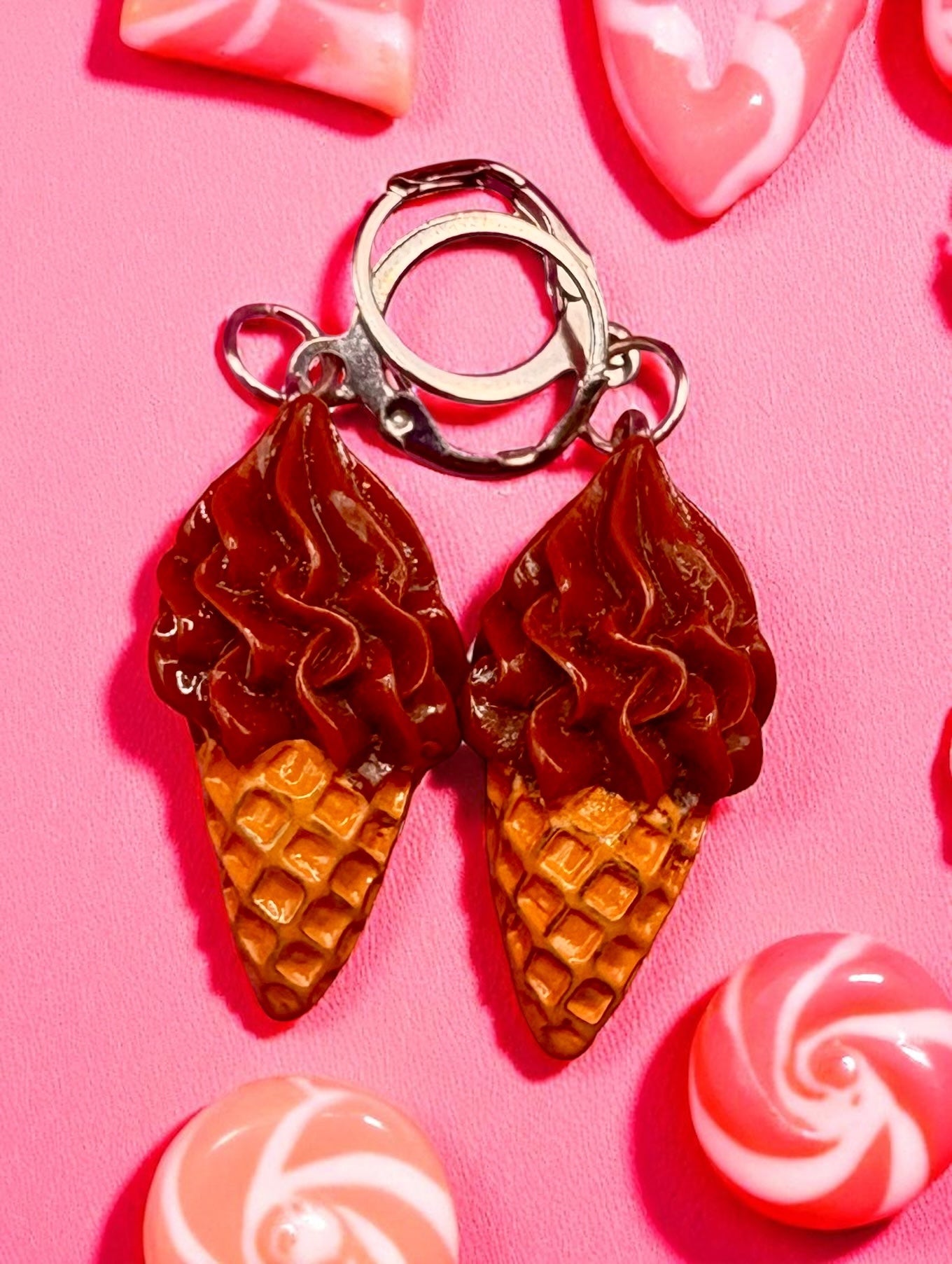 Ice cream cone-shaped  earrings on a pink background with candy decorations