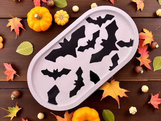 tray with bat shapes on a wooden surface with autumn leaves and pumpkins.