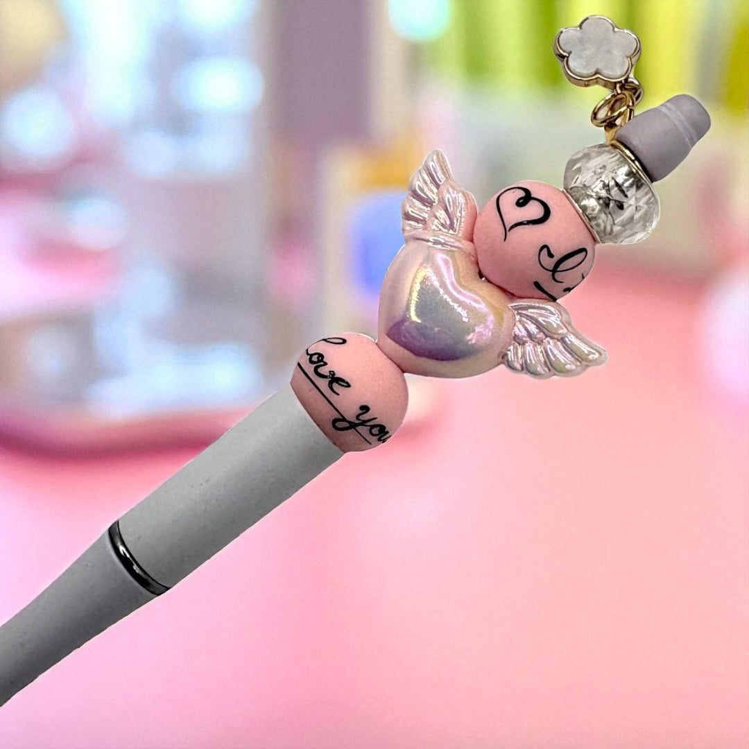 Pen with angel wing and heart-shaped cap on a blurred background