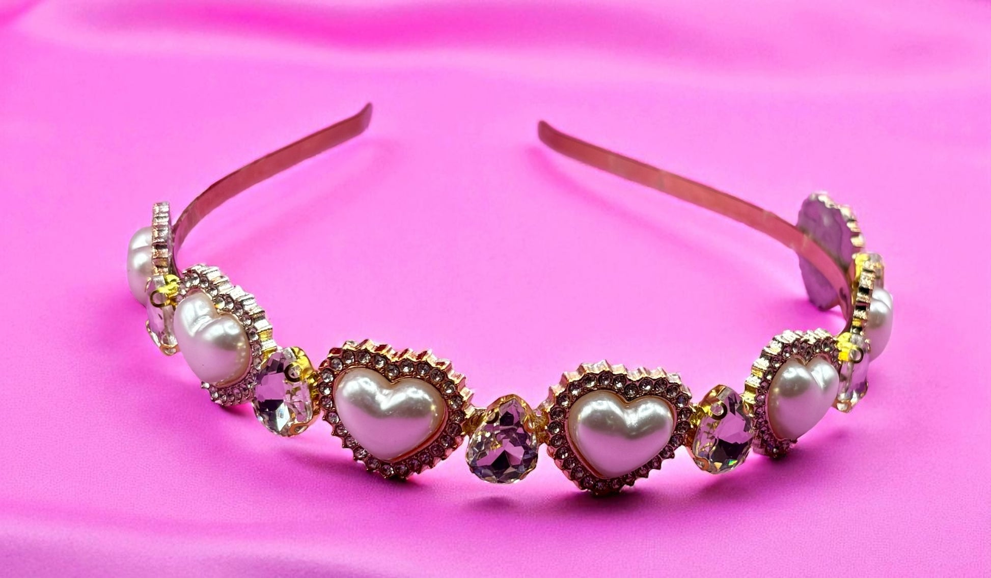 Decorative headband with heart-shaped pearls on a pink background