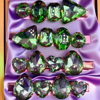 Green gemstone hair clips on a purple satin background