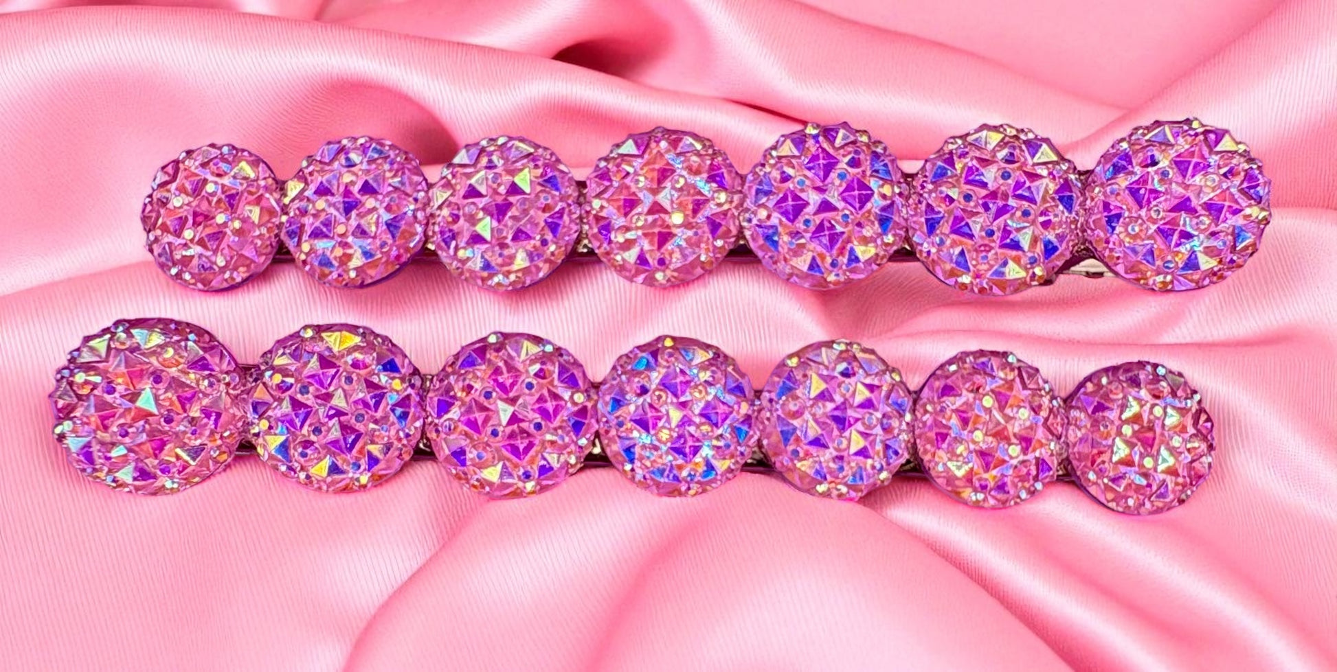 Set of pink and purple glittery hair ties on a pink satin background